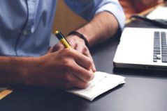 man taking notes at computer
